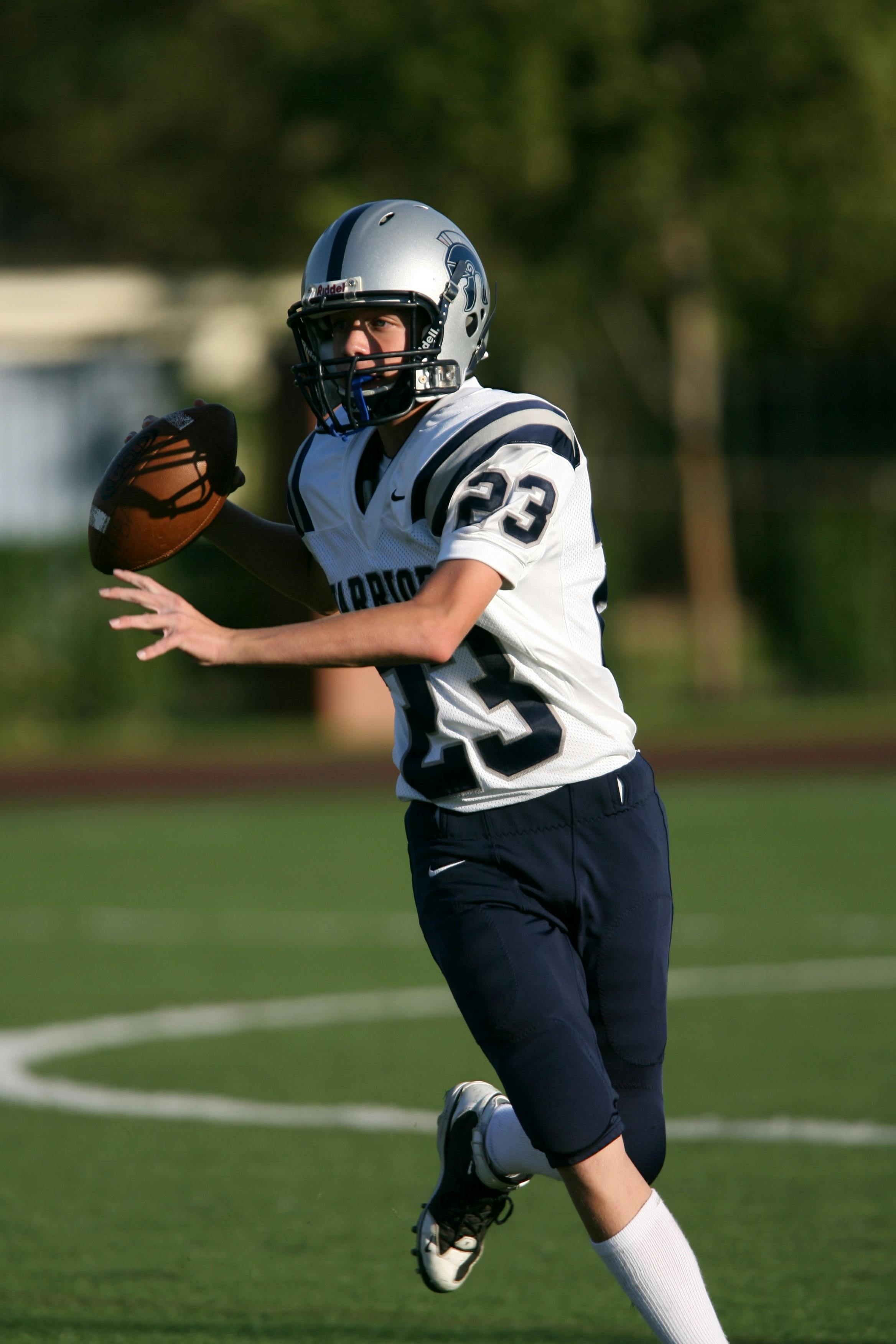 Man in White and Black Football Jersey Playing on Field during