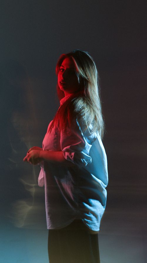 Free A dramatic portrait of a fashion model with contrasting red and blue lighting, creating a moody atmosphere. Stock Photo