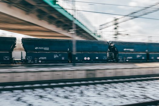 Blurry motion of a PKP Cargo train swiftly moving in Trzebinia, Poland's winter landscape.