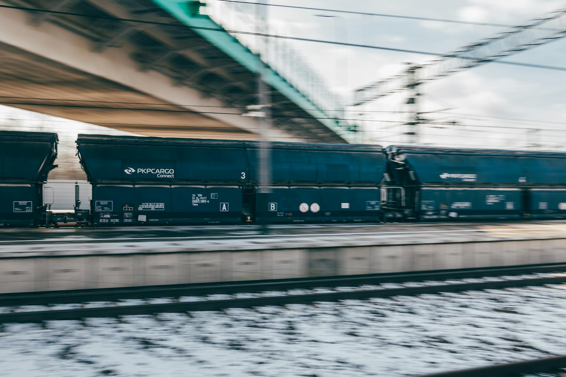 Blurry motion of a PKP Cargo train swiftly moving in Trzebinia, Poland's winter landscape.