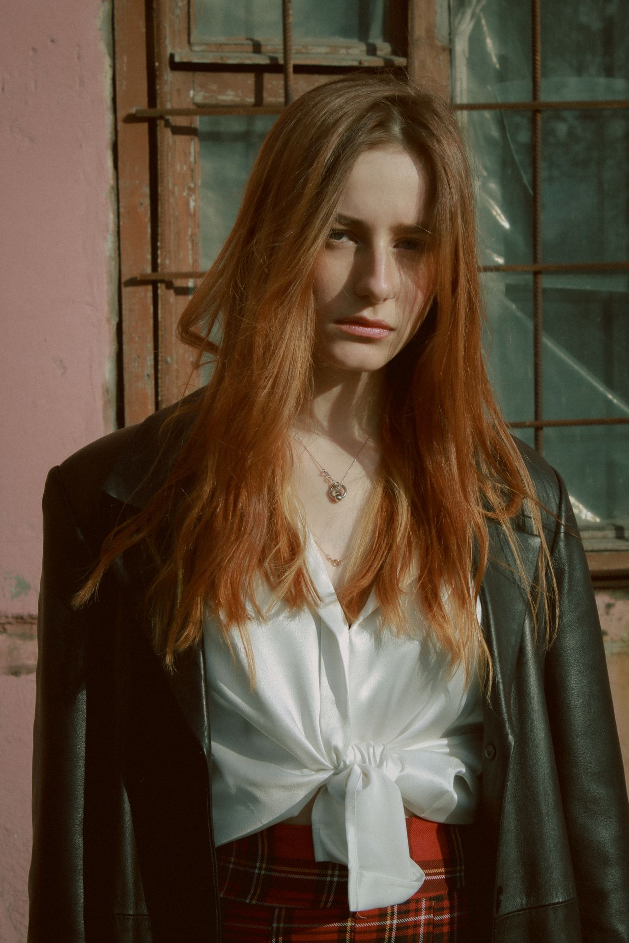 Woman in a white satin blouse, leather jacket and plaid skirt