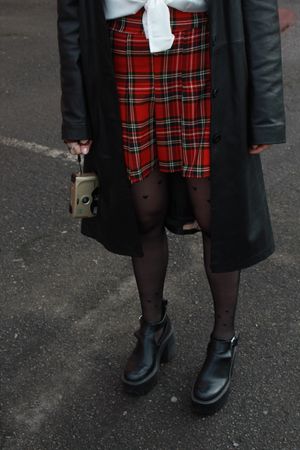Plaid skirt and boots outfit photographed on asphalt. Photo by Nastasya Banana on Pexels.