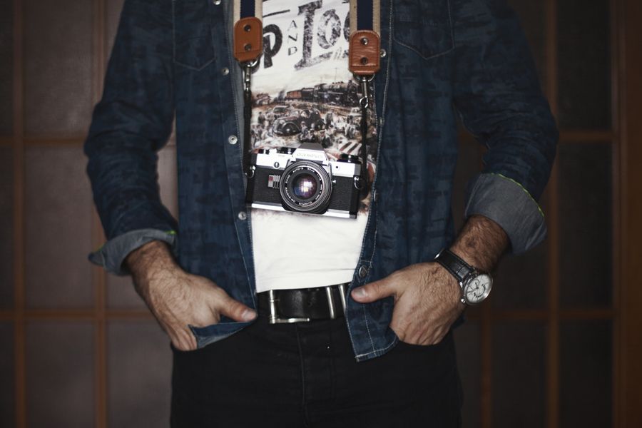 Adult male photographer in denim jacket holding a vintage camera.