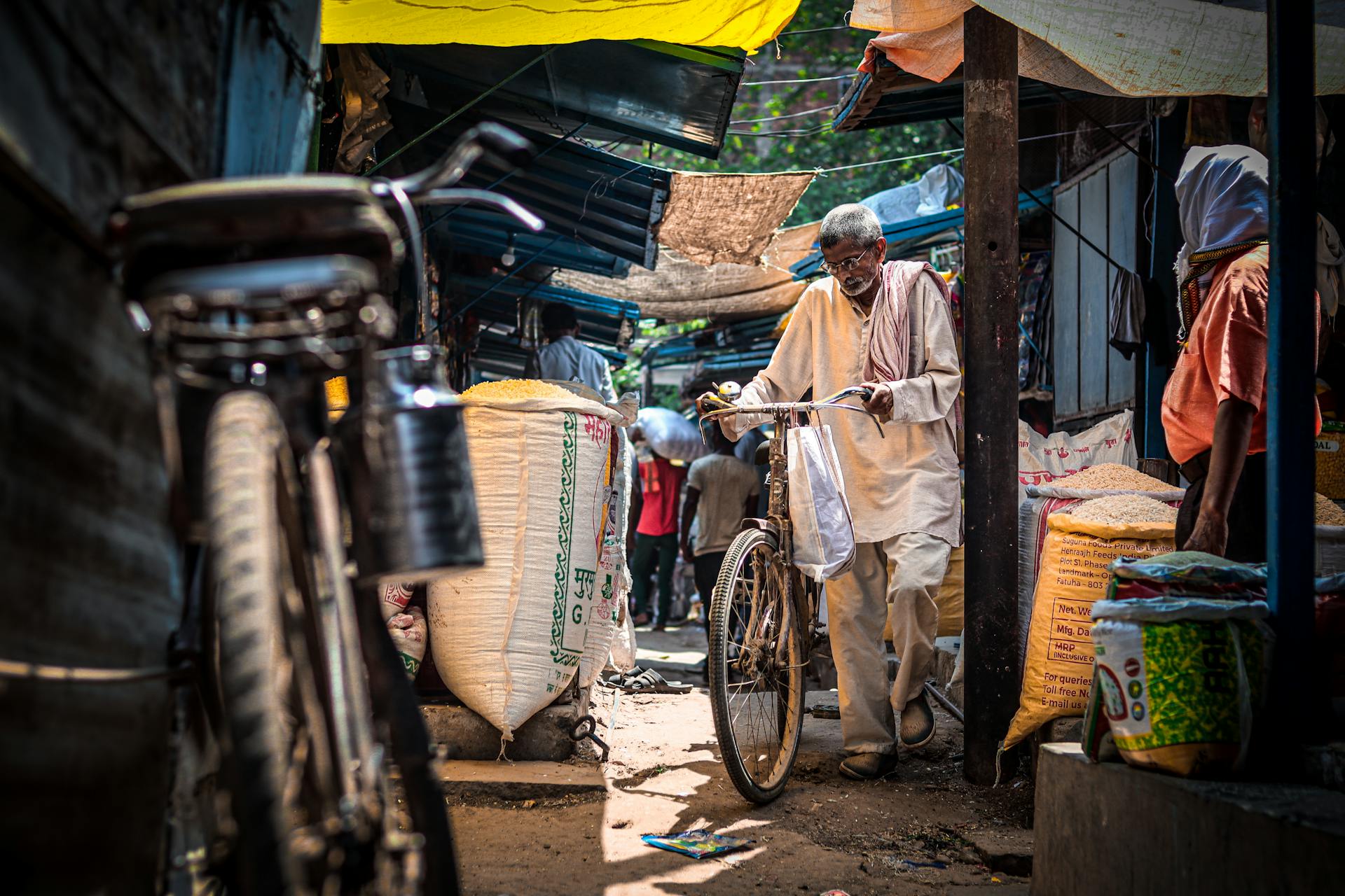 A detailed view of a bustling Indian market in Ballia with a man pushing his bicycle.