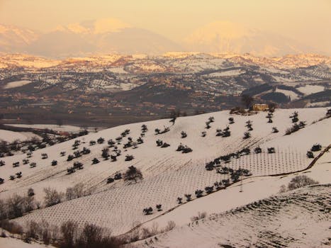 Captivating view of a snow-covered Italian landscape with rolling hills at sunrise.