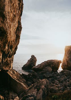 Majestic view of sunrise over a rocky seashore with prominent cliffs and serene waters.