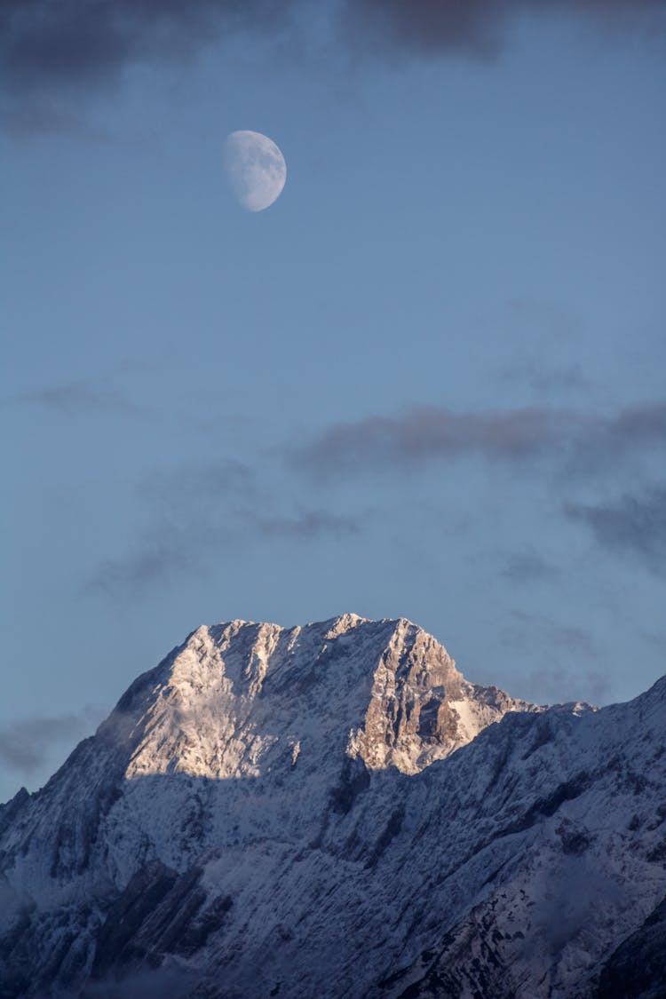 Moon Over Mountain Peak In Snow