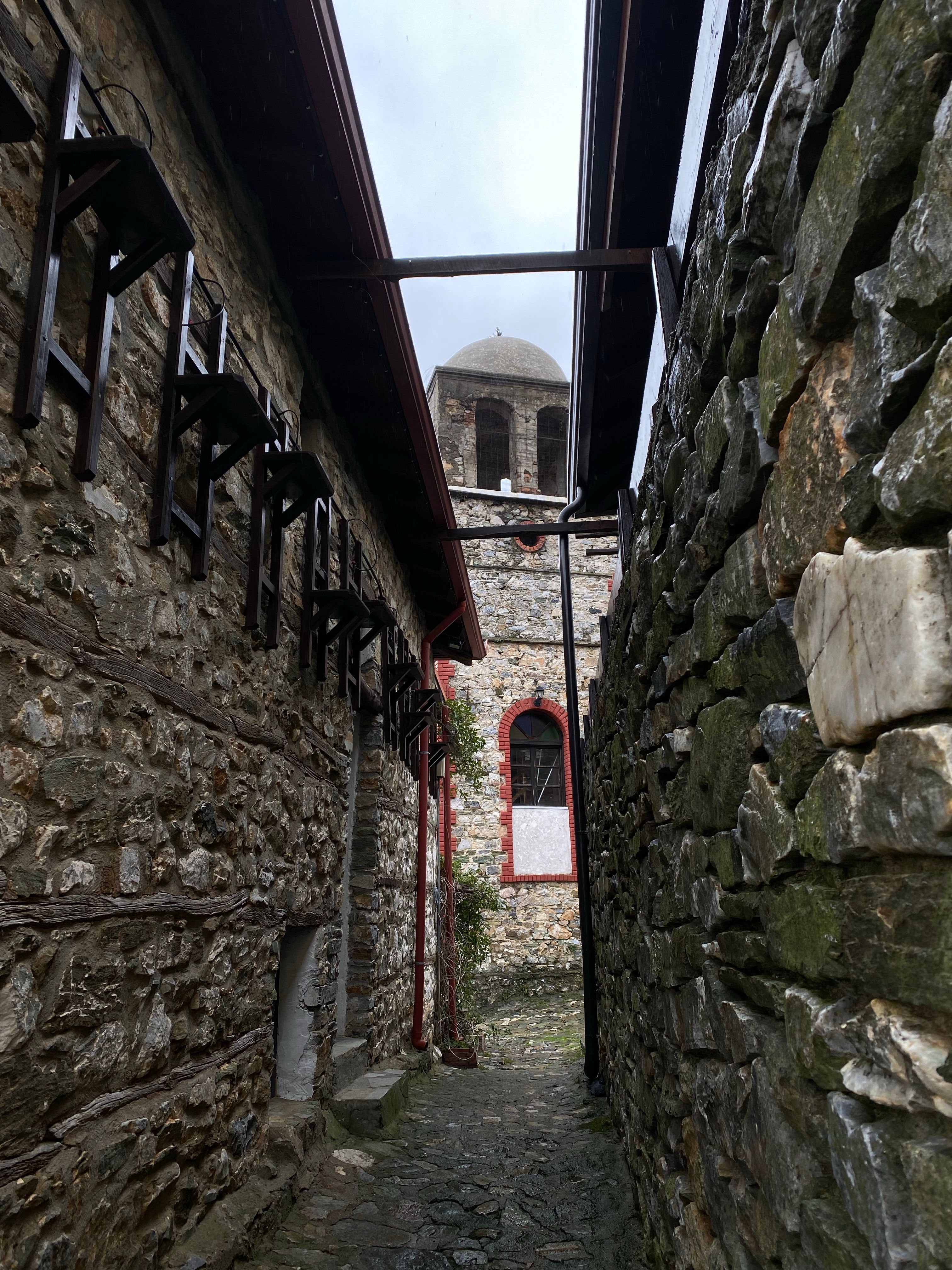 Stone alley with ancient architecture in Palaios Panteleimonas, Greece, showcasing a narrow, historic ambiance.