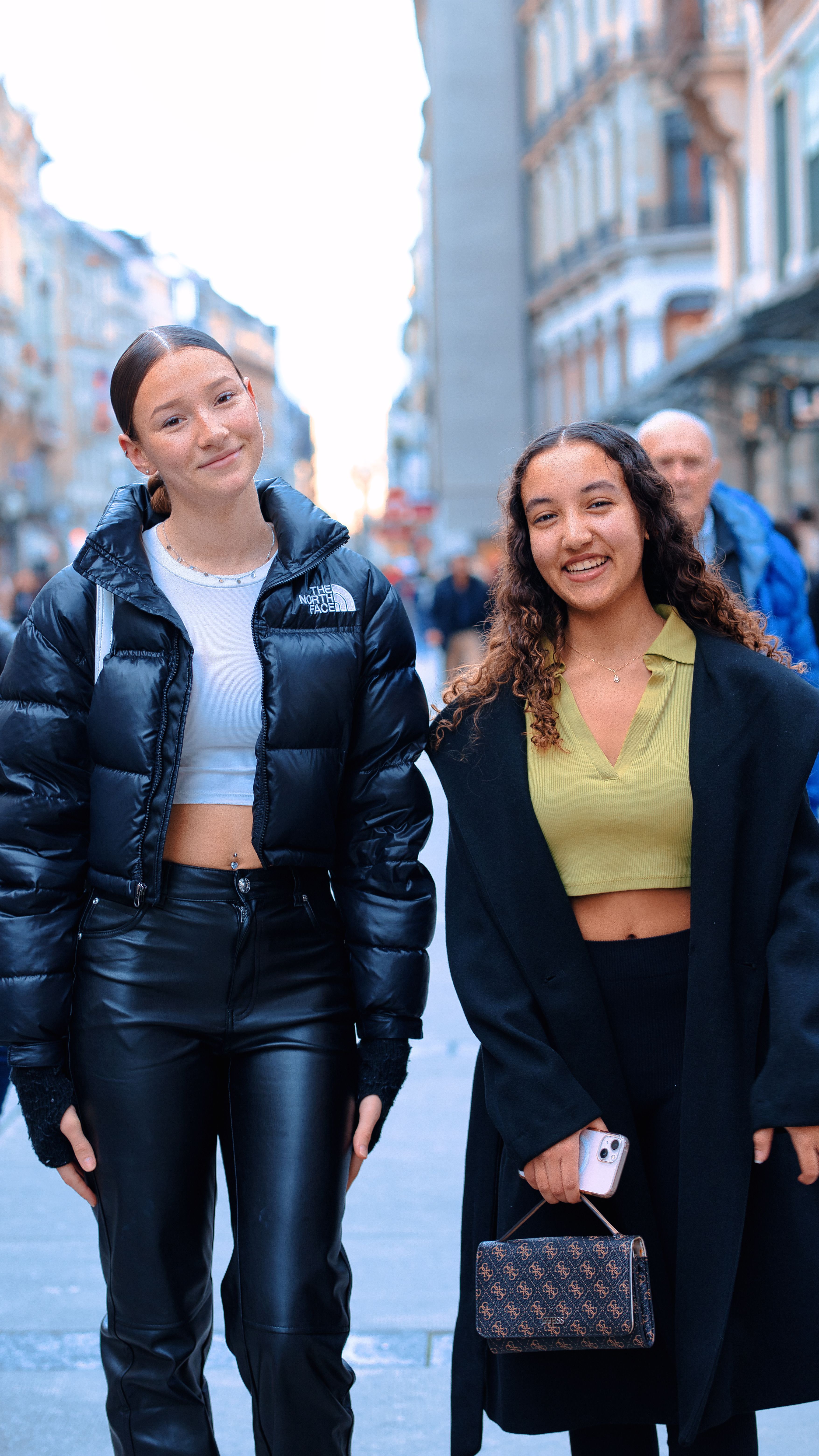 Two young women enjoying a stroll in an urban setting, showcasing vibrant fashion styles.