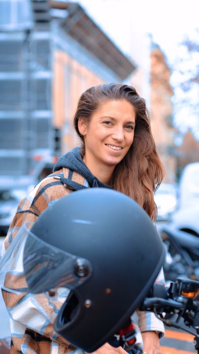 Portrait of a smiling woman with a motorcycle helmet in a city street setting