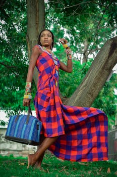 Stylish woman in checkered dress posing outdoors with a blue bag.