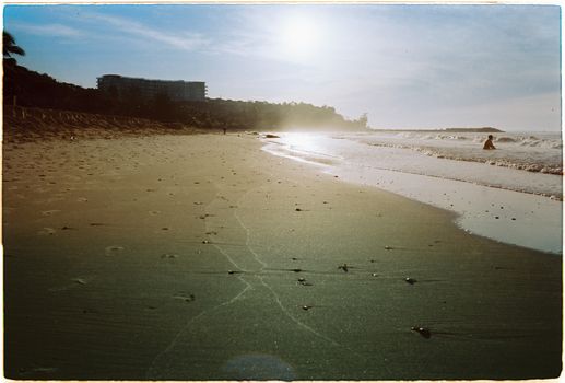 Tranquil beach landscape at sunset with soft waves and sandy shore.