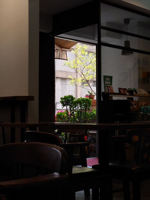 Free A cozy indoor cafe setting with chairs and table, overlooking a sunny outdoor scene. Stock Photo