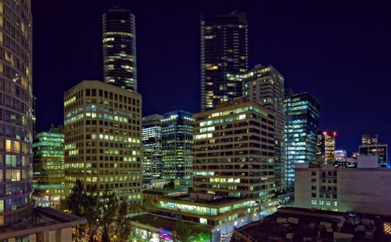 A bustling cityscape at night showcasing illuminated skyscrapers and vibrant lights in a modern urban setting.
