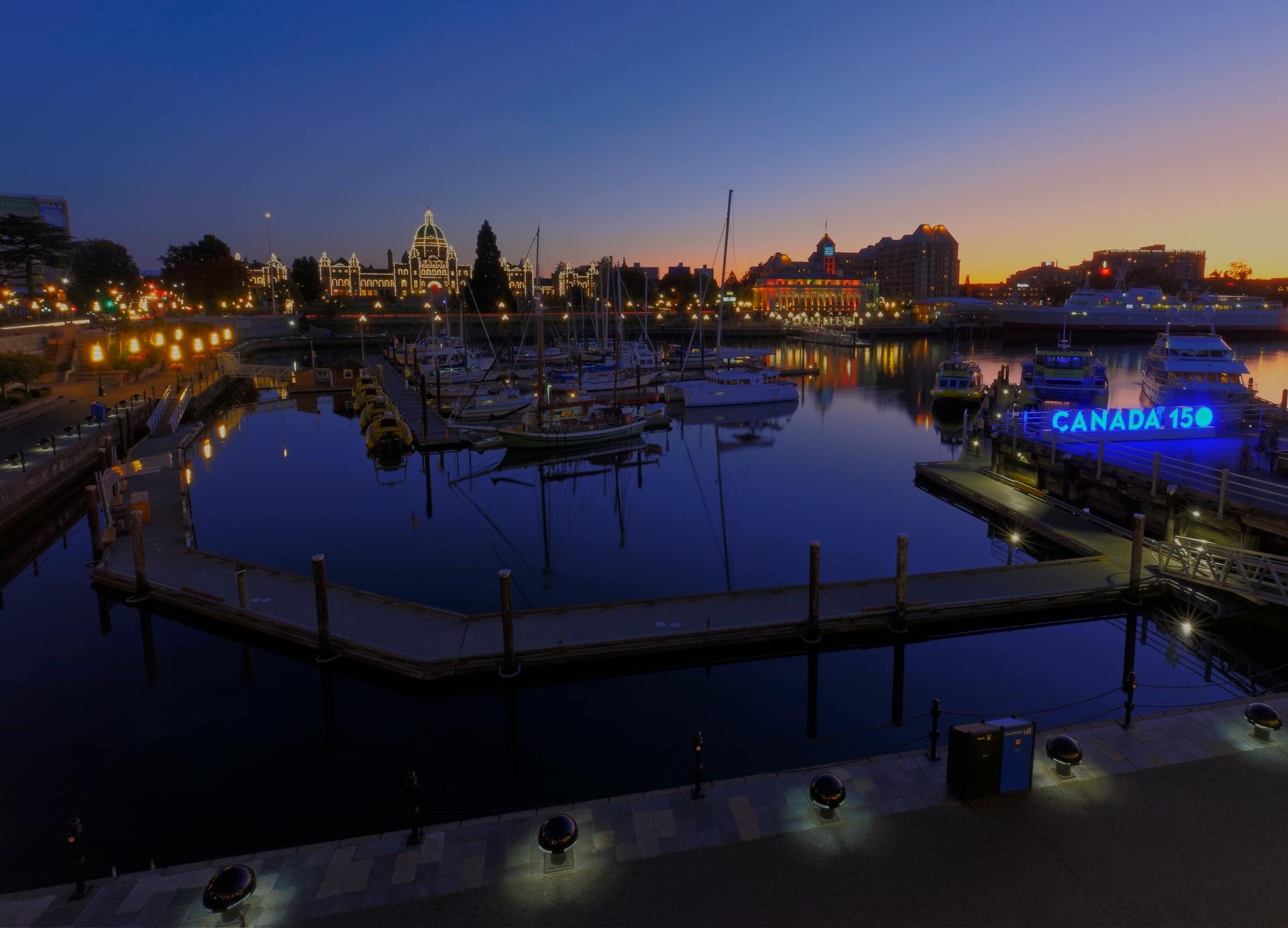 Beautiful evening view of Victoria Harbor with boats and illuminated skyline during dusk.