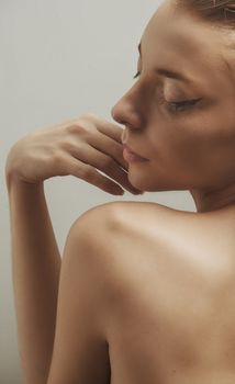 Side profile of an elegant woman posing with her eyes closed against a neutral background.