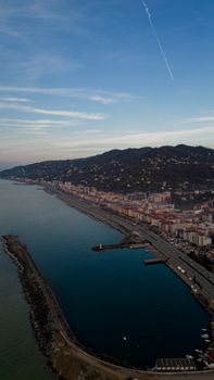 Stunning aerial view of a coastal town with hills and a blue sky backdrop at daytime.