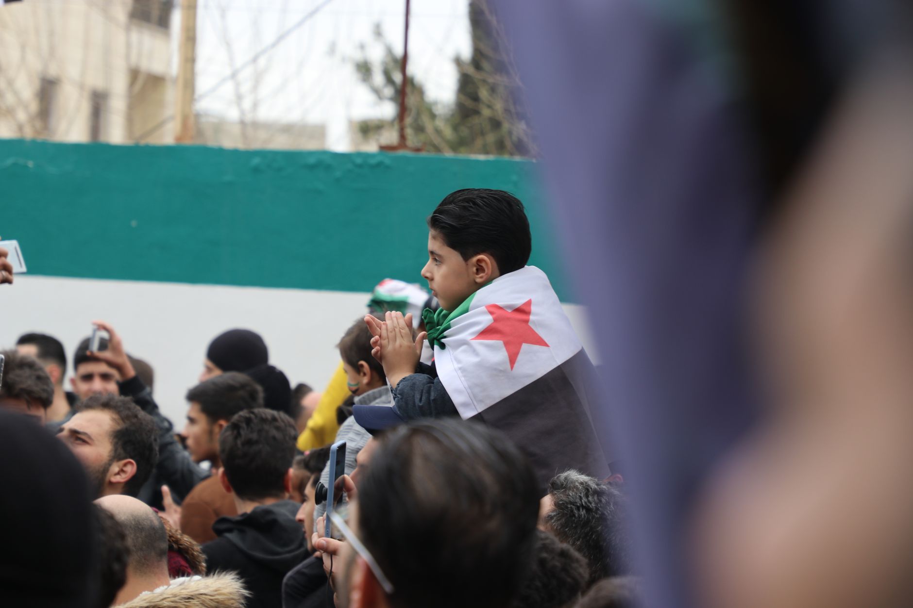 Algeria supporters waving national flags outside a crowded stadium, vivid green and white colors
