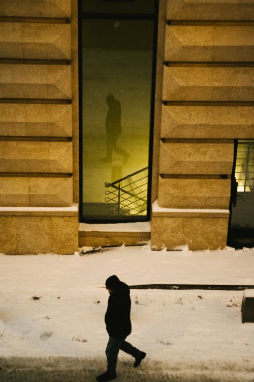 Free A winter street scene with a lone pedestrian and reflections in a window. Stock Photo