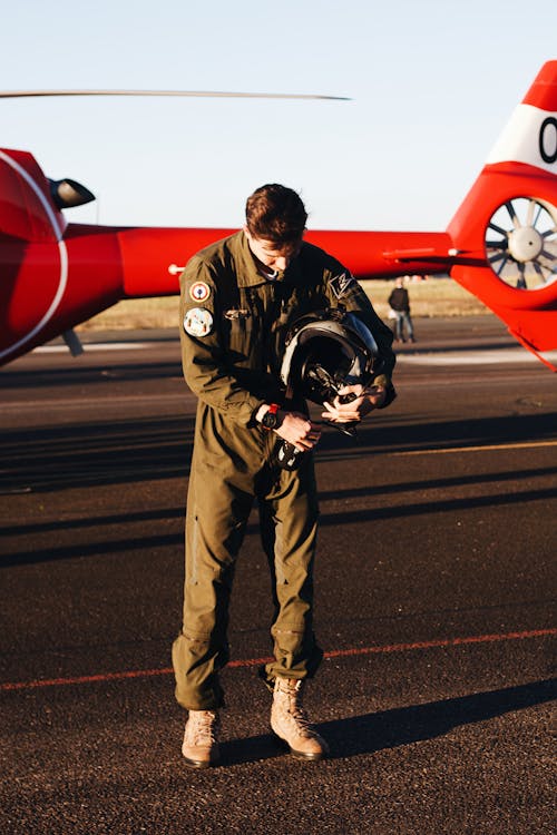 A Pilot in a Suit Holding a Helmet Standing in front of an Airplane 