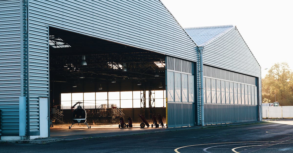 A modern industrial hangar exterior with a helicopter visible, offering spacious interior views.