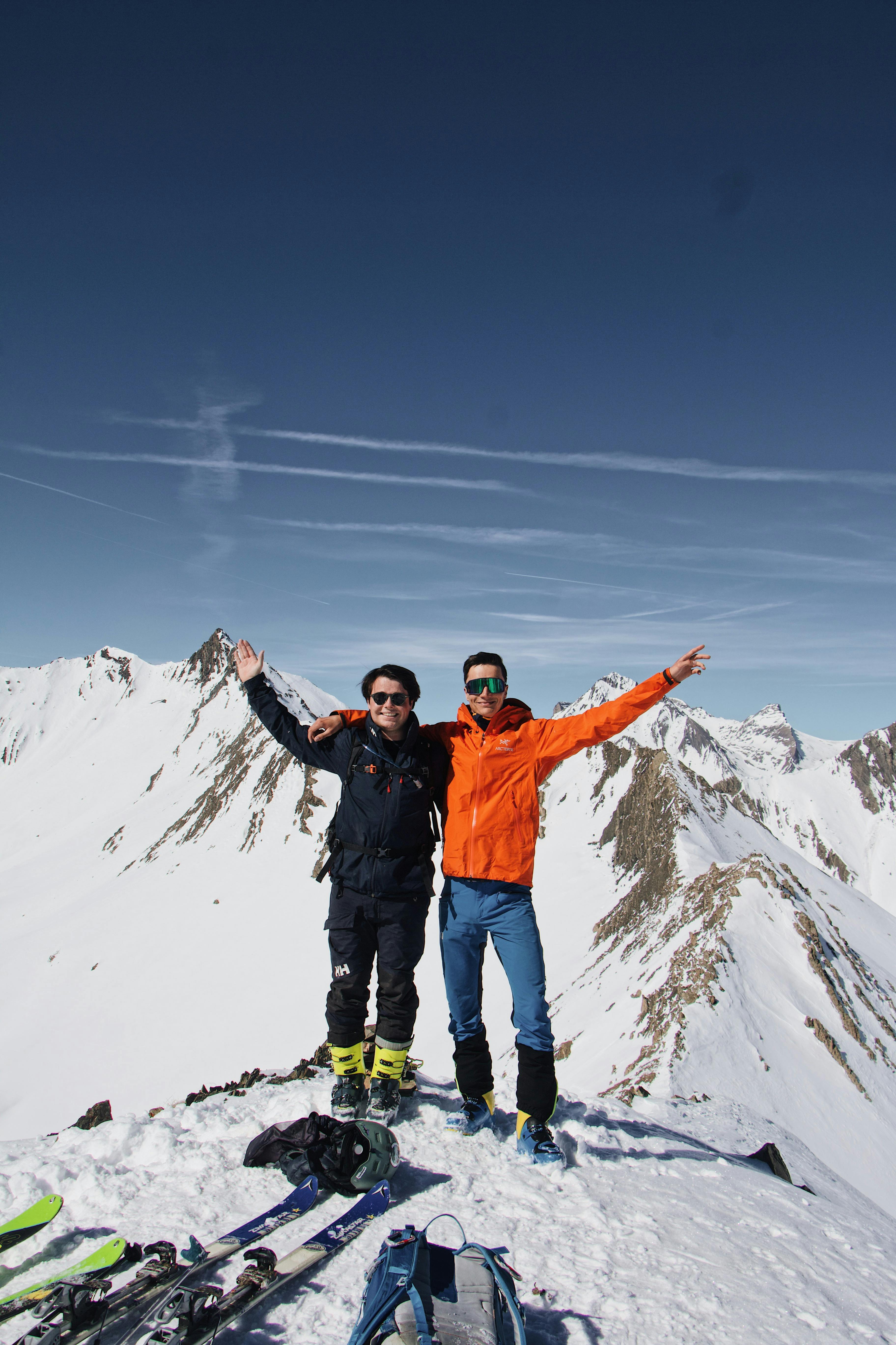 two men standing on top of a snowy mountain