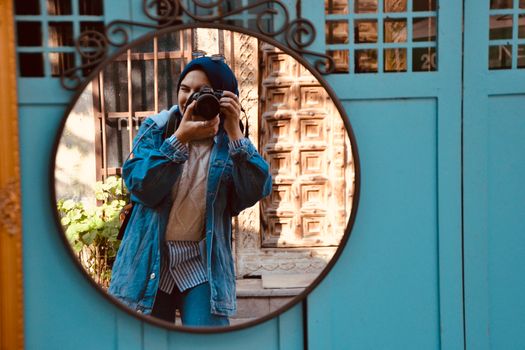 A woman takes a photo through a mirror reflection in an artistic setting.