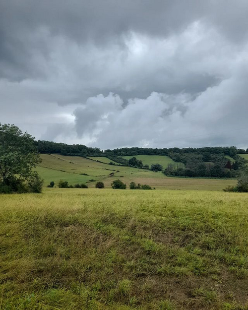 Free A serene landscape of rolling hills with dramatic stormy clouds overhead, perfect for nature themes. Stock Photo