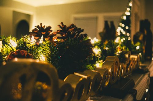 Free Warm and cozy Christmas mantel decorated with pine cones, lights, and festive ornaments. Stock Photo