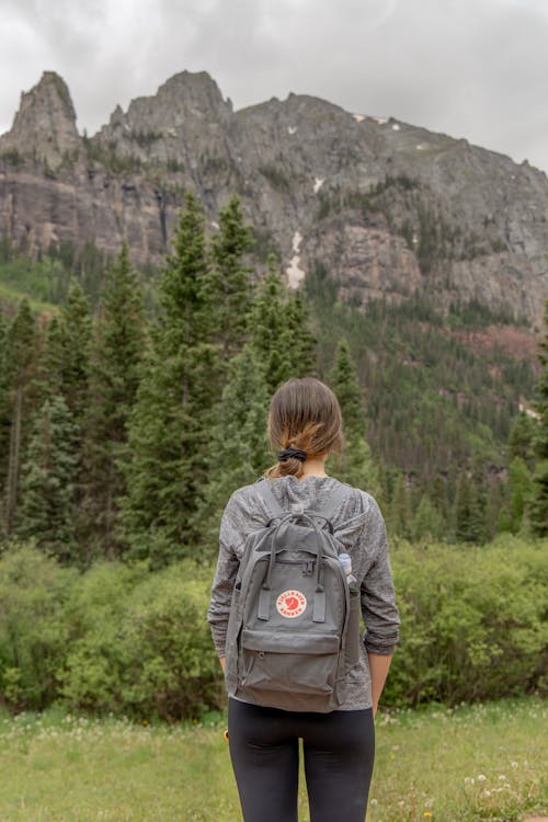 Woman Standing with Backpack with Forest and Mountains behind