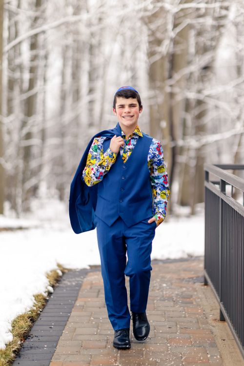 Free Young man in a colorful suit walking confidently in a snowy forest setting. Stock Photo
