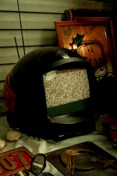 Vintage helmet-shaped TV with static screen among retro collectibles at a market stall.