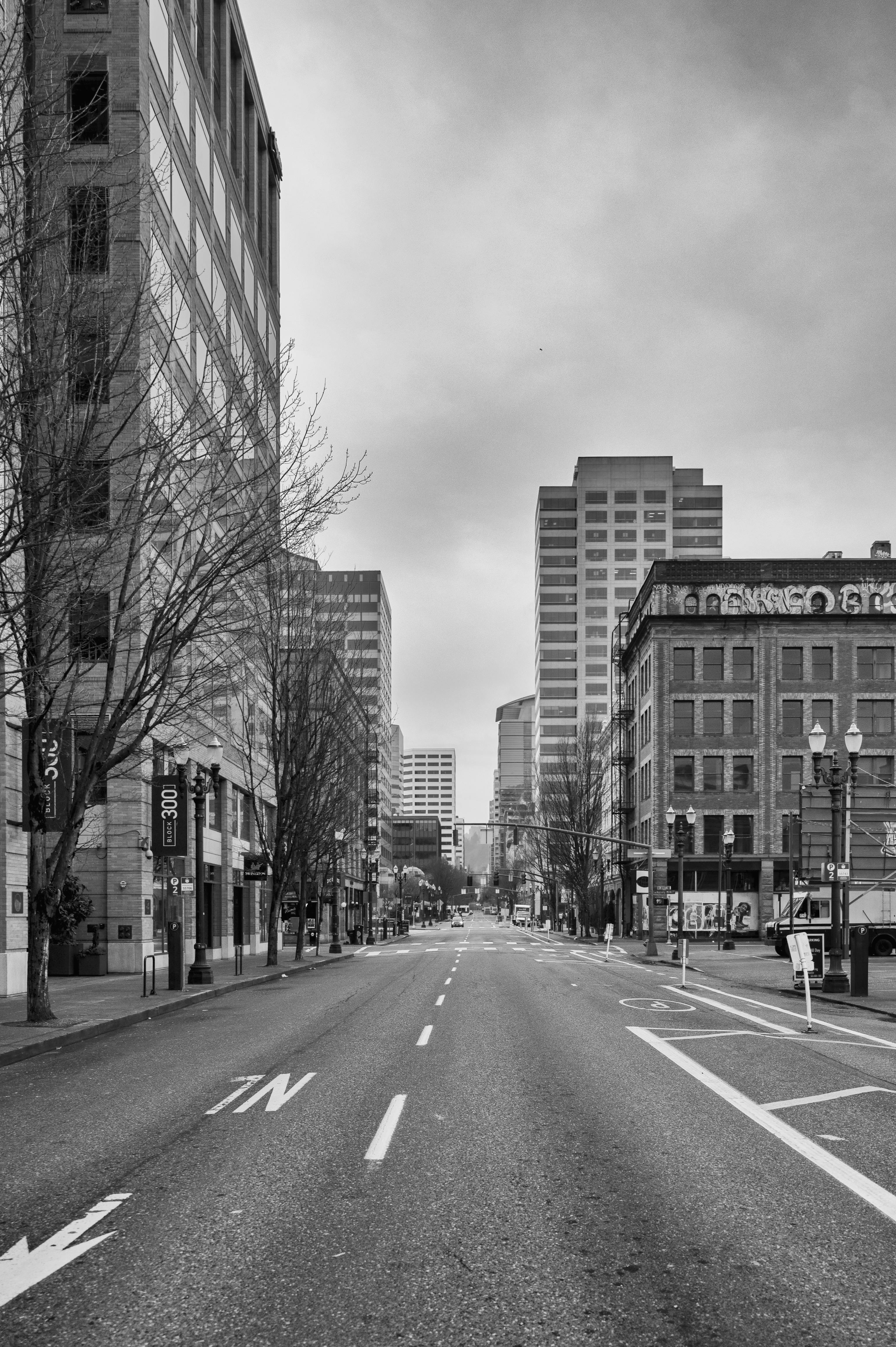 A deserted grayscale urban street lined with tall buildings and empty sidewalks.