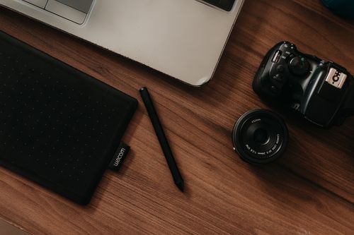 Overhead view of a wooden desk workspace — photo by Kawê Rodrigues on Pexels