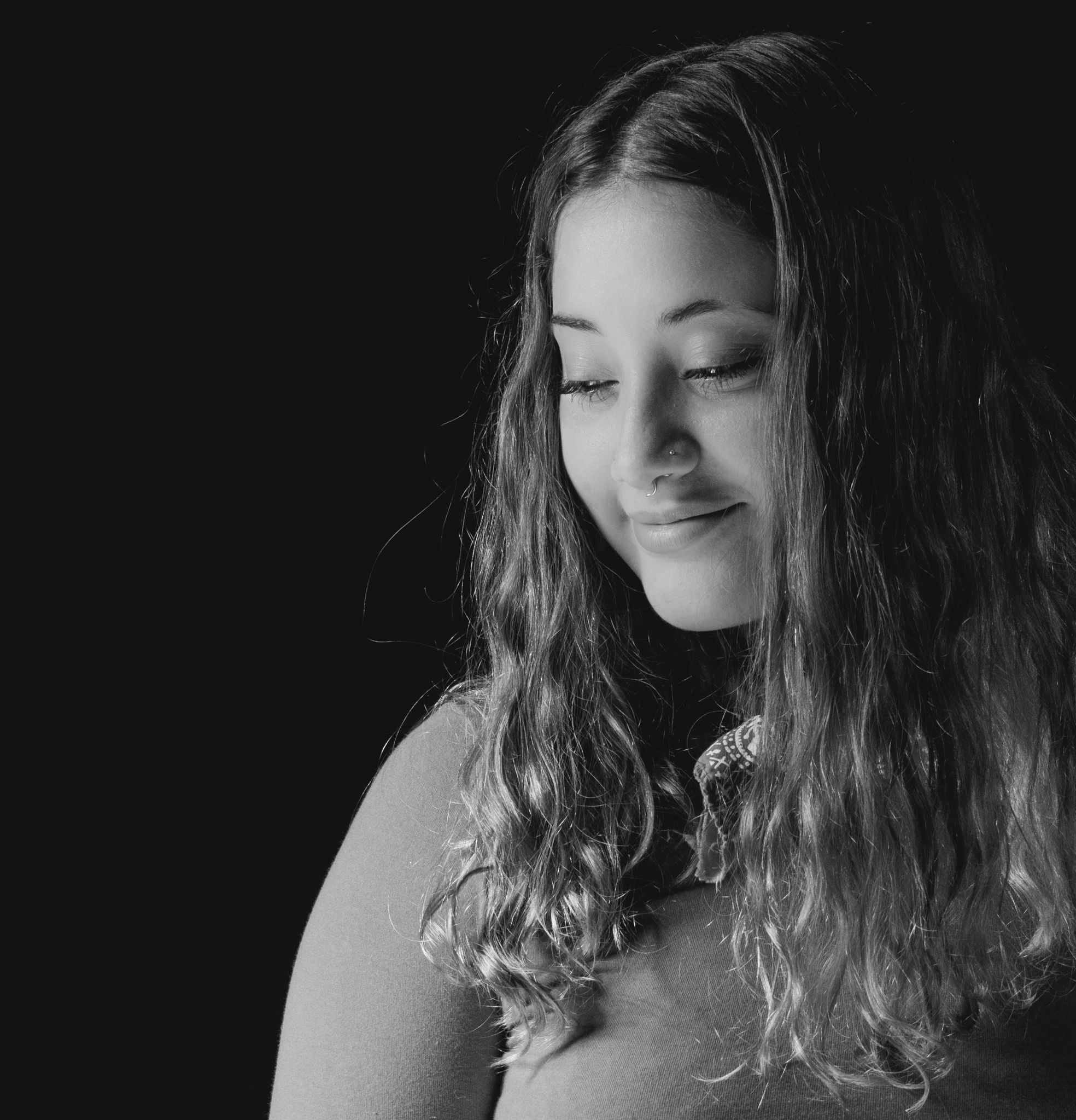 A captivating black and white studio portrait of a smiling woman with long hair, expressing elegance.