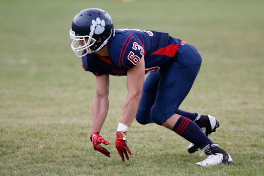 A focused American football player in uniform prepares to make a move on the field.