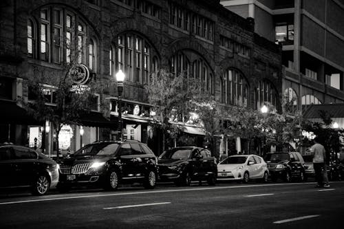 Free Grayscale Photography of Vehicles Parked Near Building Stock Photo
