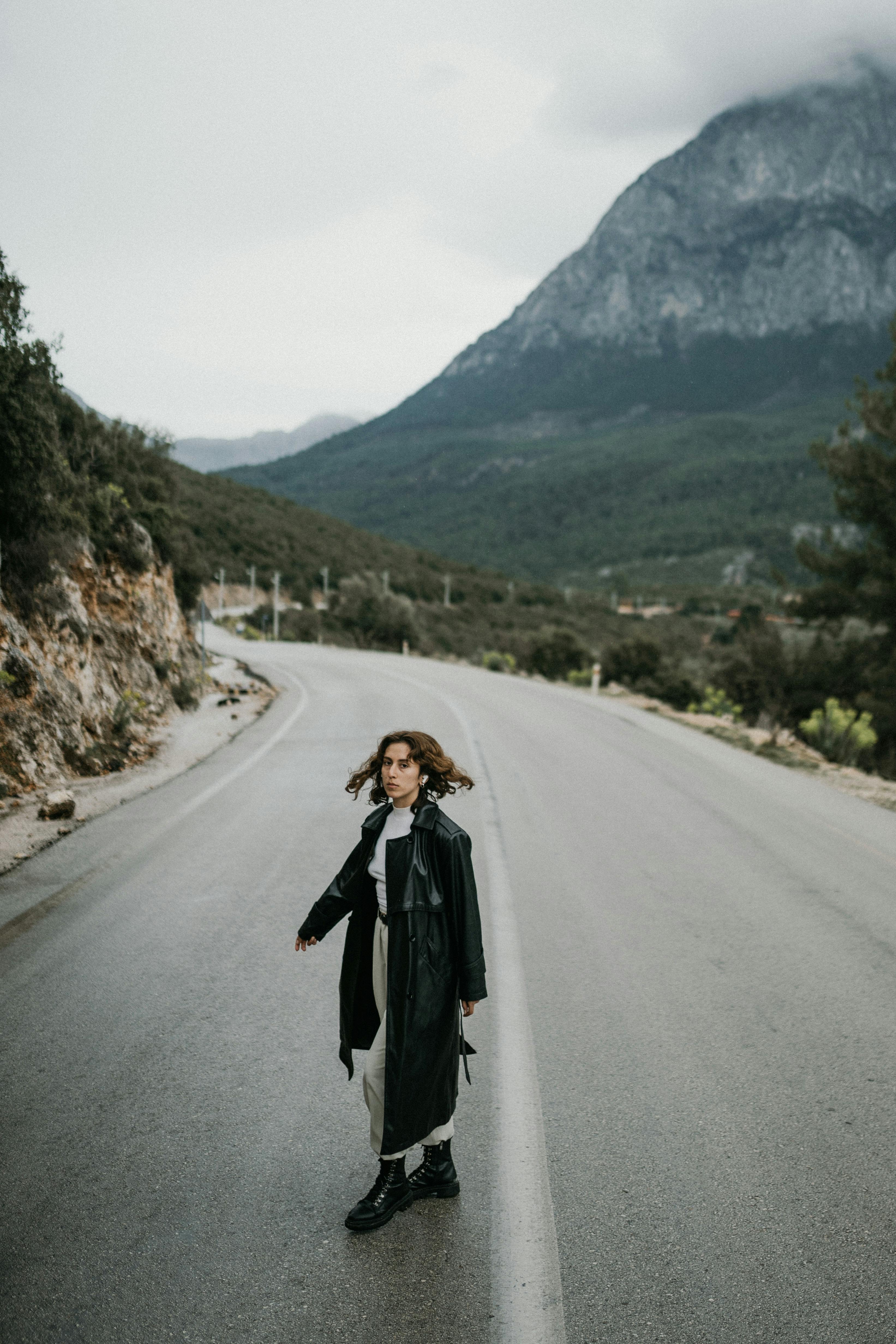 Woman in a black coat walking on a deserted mountain road in Antalya, Turkey.