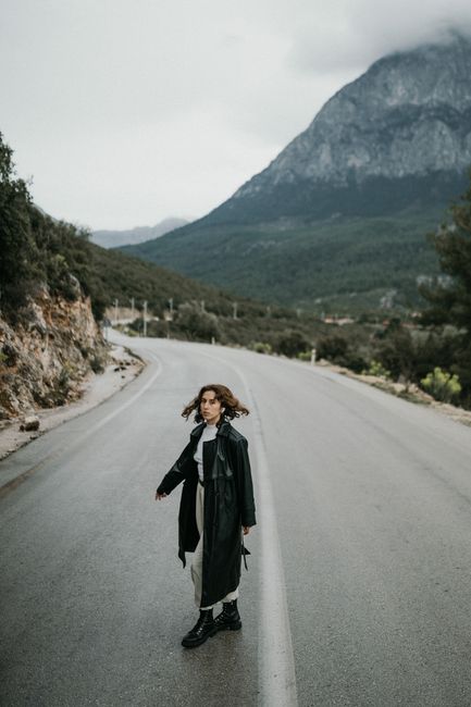 Woman in a black coat walking on a deserted mountain road in Antalya, Turkey.