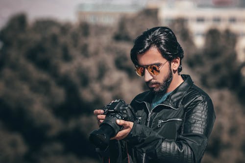 Selective Focus Photography of Man Holding Dslr Camera