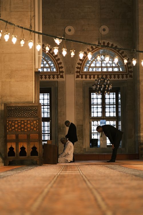 Free Men engaged in prayer inside an Ottoman architecture mosque, illustrating faith and tradition. Stock Photo