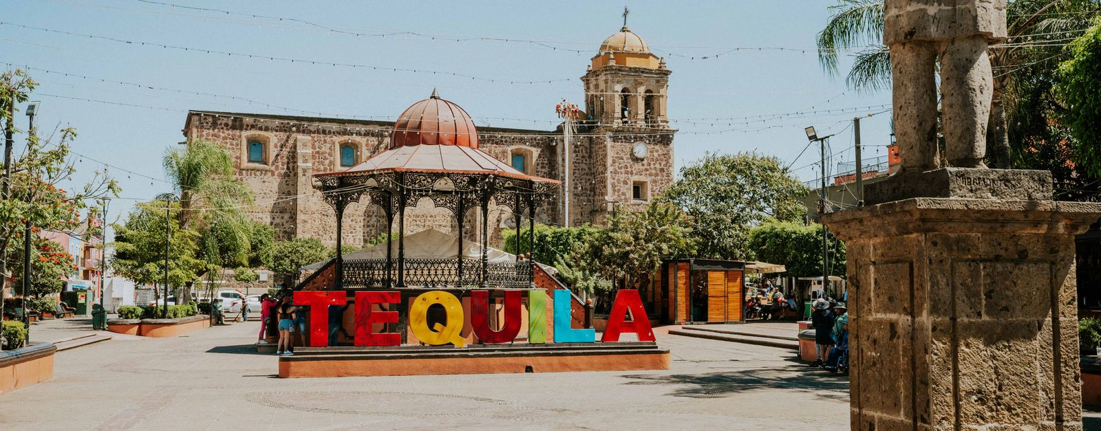 Vibrant Tequila sign in sunny Mexican plaza with historic architecture.