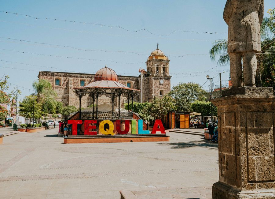 Vibrant Tequila sign in sunny Mexican plaza with historic architecture.