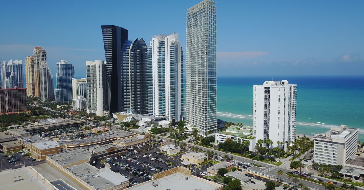 Drone shot of Sunny Isles Beach, FL skyline with ocean and skyscrapers.
