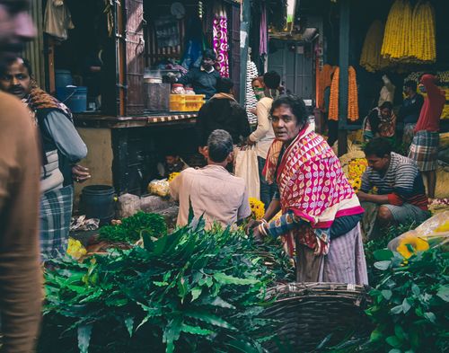Free Bustling marketplace in Kolkata with people selling colorful flowers. Stock Photo