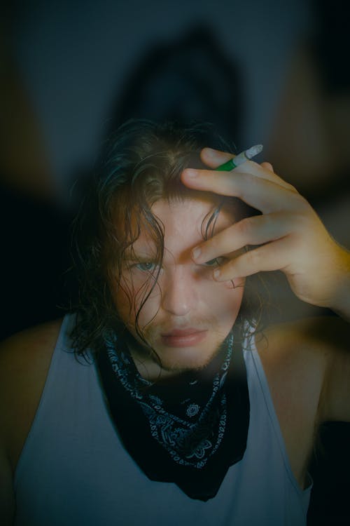 Young Man Wearing a Tank Top and a Bandana Smoking a Cigarette