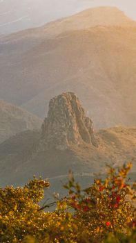 A breathtaking view of a rock formation surrounded by autumn foliage, captured at sunset.