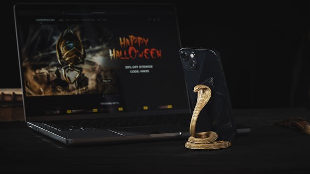 Metallic cobra-shaped phone stand with smartphone near laptop on dark surface.