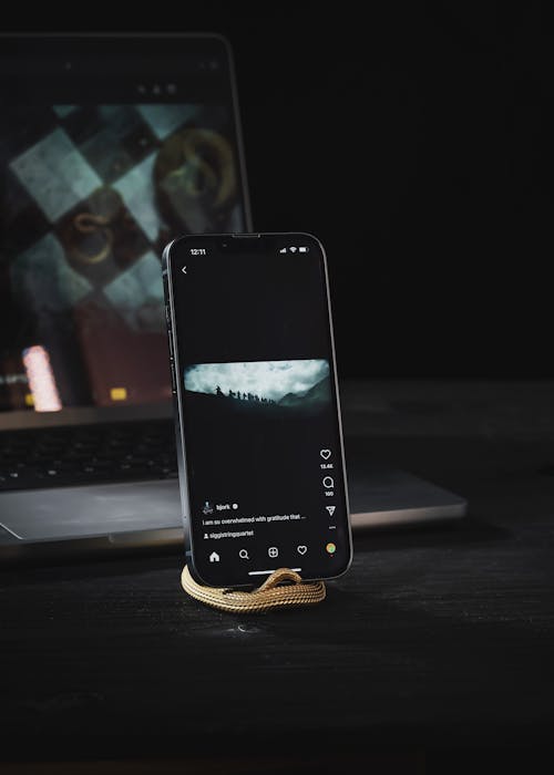 Smartphone on a Brass Phone Stand in Front of a Laptop