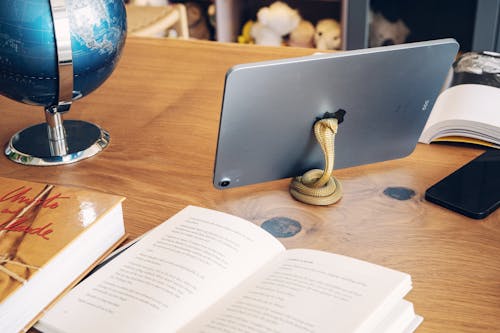 Tablet on a Brass Stand in the Shape of a Snake Among the Books on the Desk